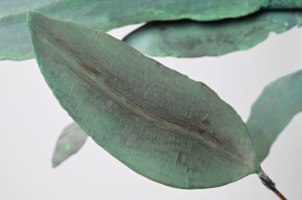 Close detail of a single verdigris-patinated copper leaf.