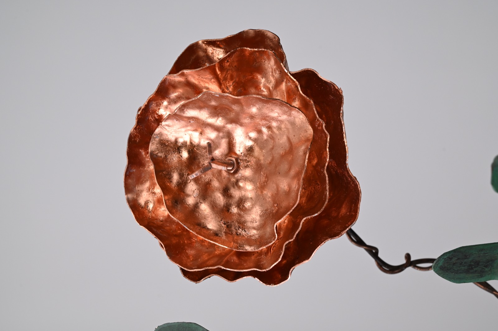 Detail of copper spearhead forms and scrolled copper wire at the crown of the stem.