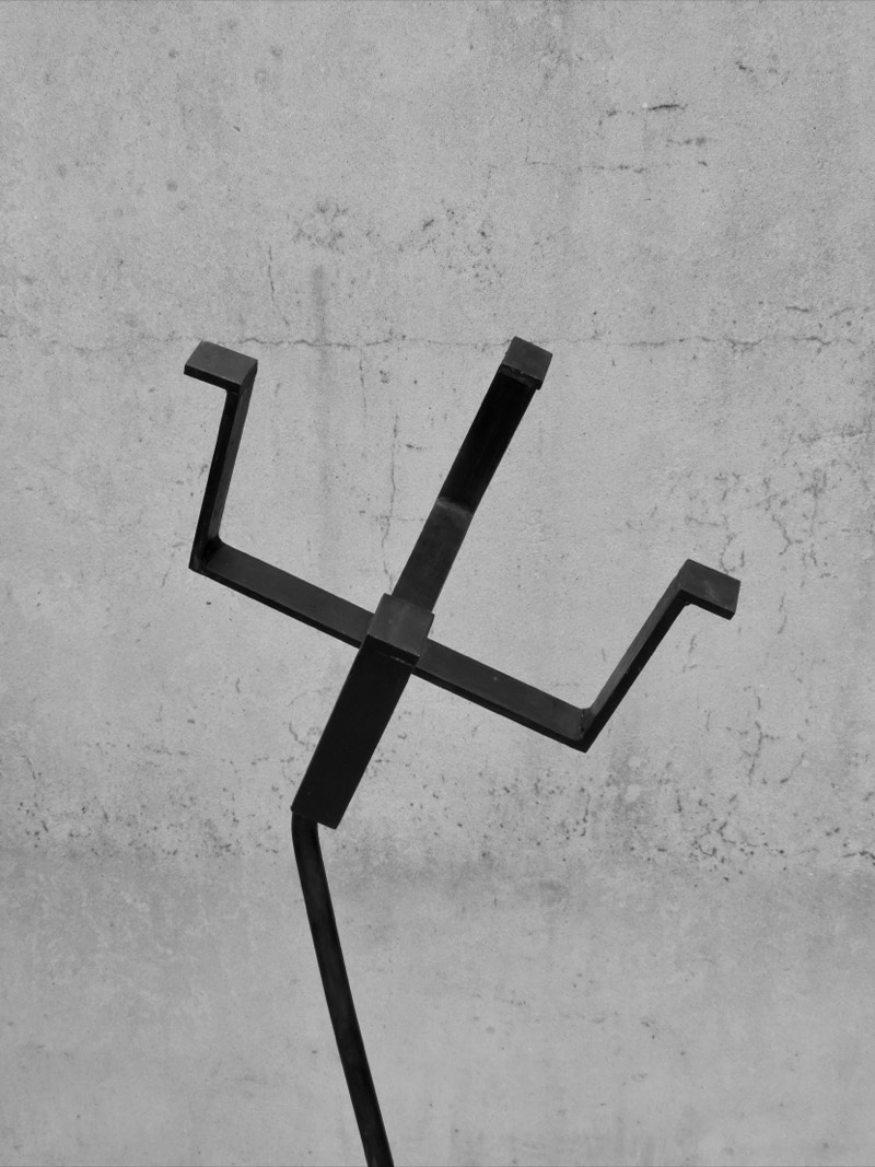 Detail of the forked crown of the forged steel figure against concrete.