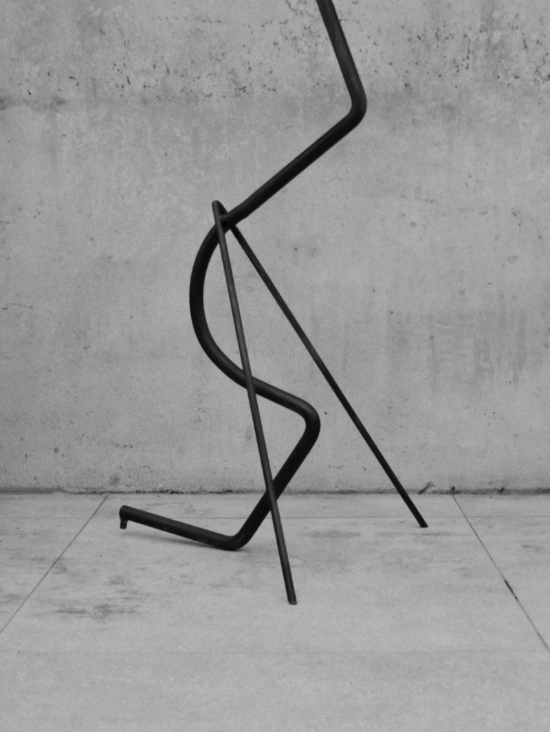 Detail of the splayed feet of the forged steel figure on a concrete floor.