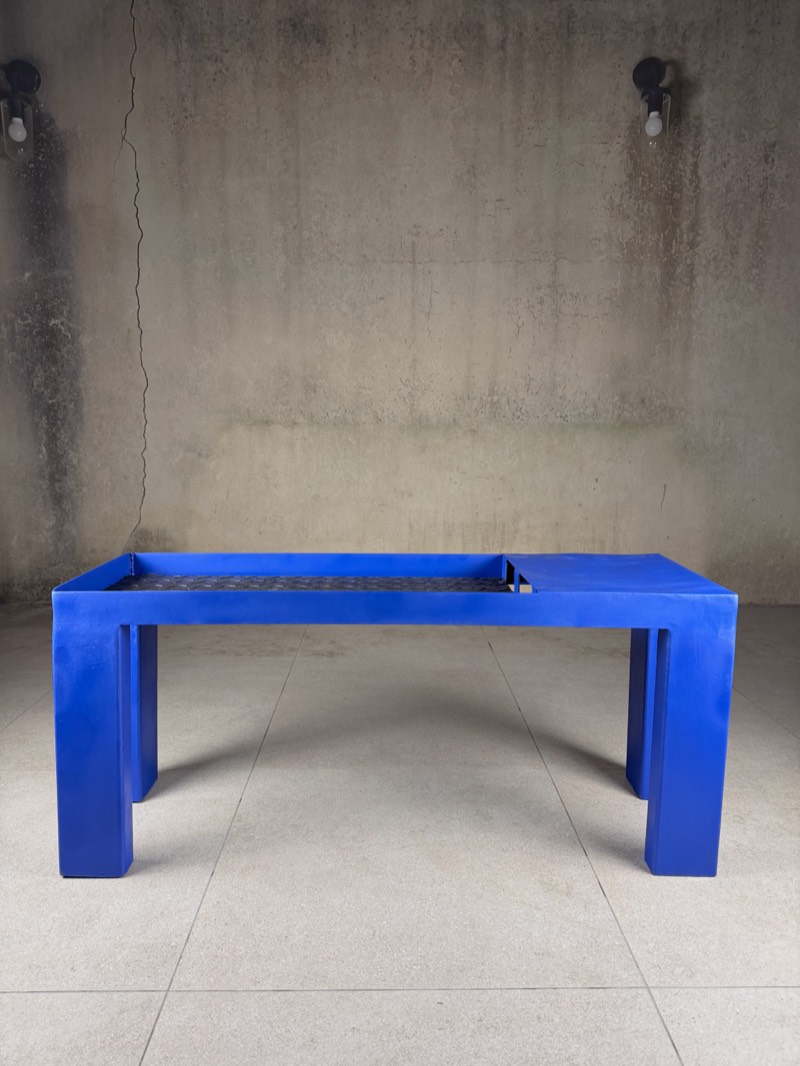 Three-quarter view of the ultramarine bench and its blocky legs.
