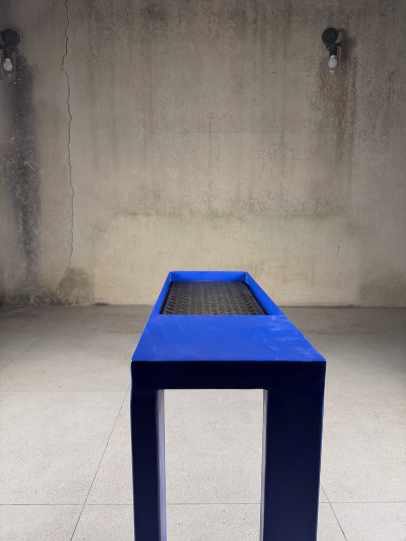 End detail of the ultramarine bench where the blue frame meets the raw chequer-plate top.