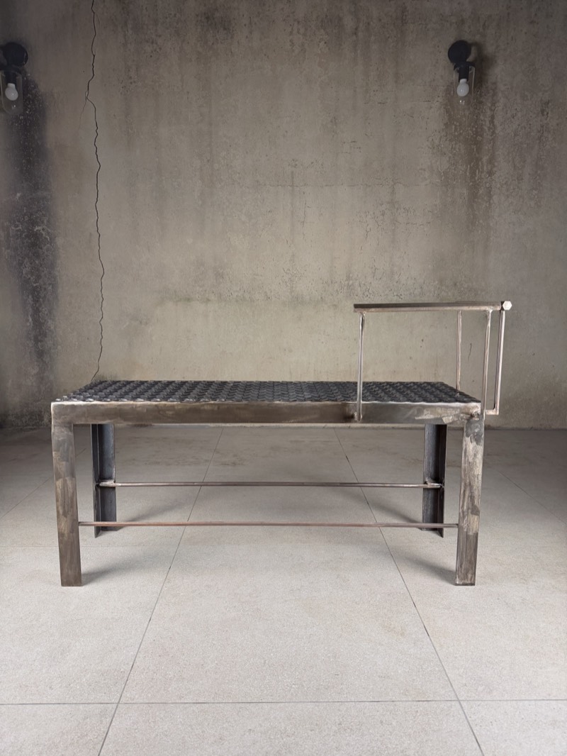 Three-quarter view of the raw steel bench showing the welded frame and rail.