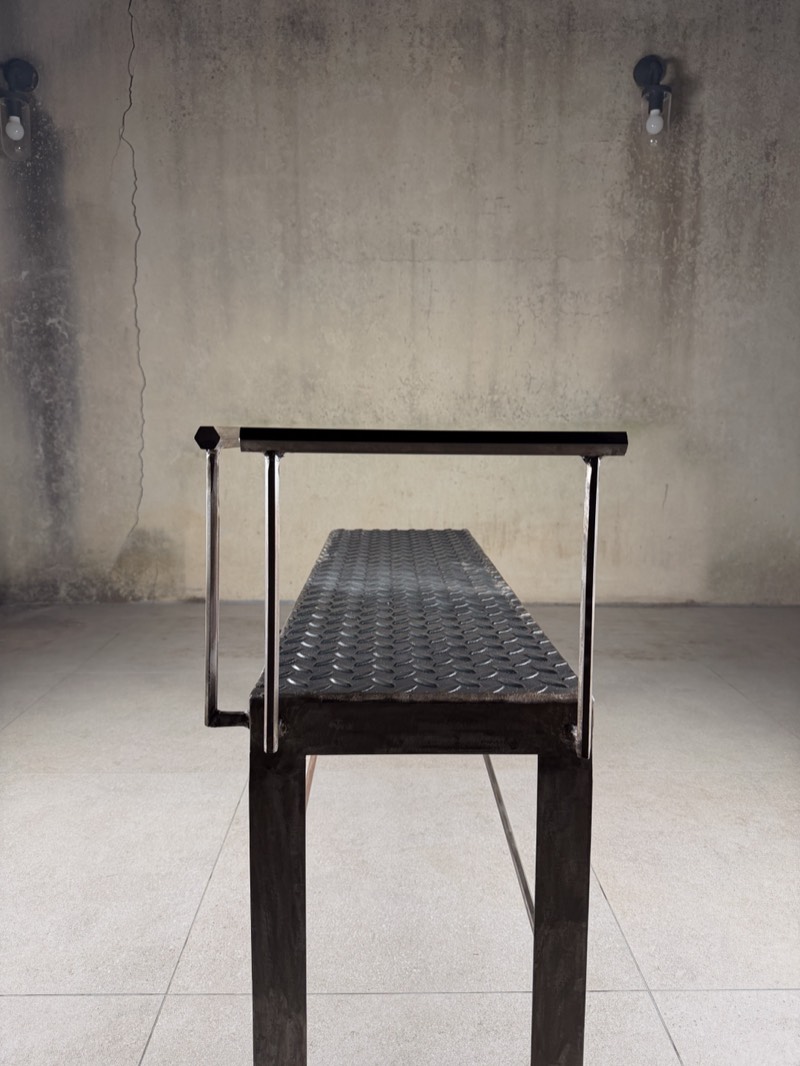 End-on view along the chequer-plate top of the raw steel bench.